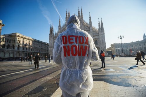 Un activista de Greenpeace frente al Duomo de Milán lleva un traje en el que se puede leer 'Detox Now'