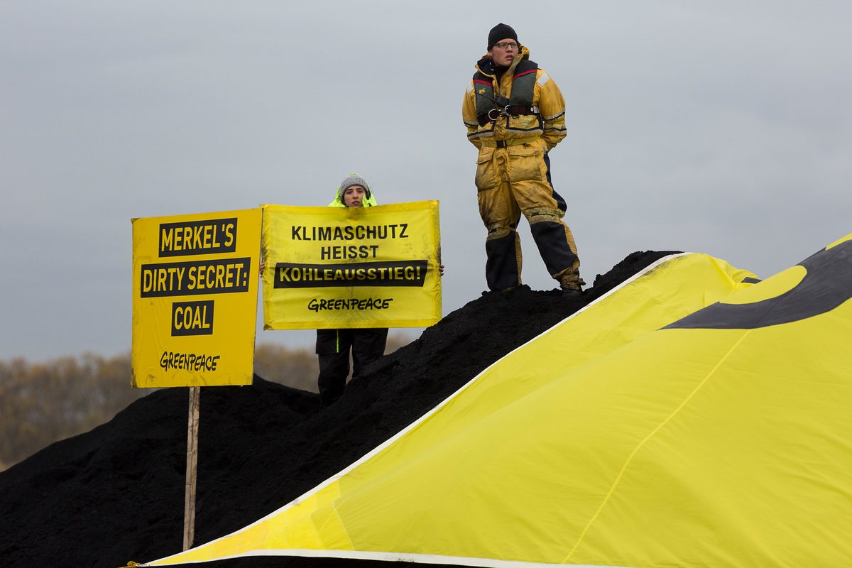 Protesta contra la importación de carbón en Alemania. En la imagen, activistas de Greenpeace sobre una montaña de carbón tienen pancartas que dicen: El carbón es el sucio secreto de Merkel