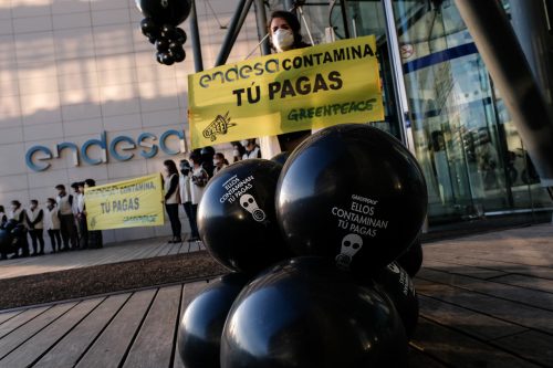 Activistas de Greenpeace sostienen globos en los que se puede leer 'Ellos contaminan tú pagas' frente a la sede de Endesa en Madrid