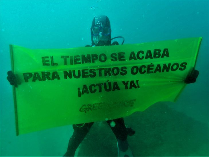 Submarinista de Greenpeace muestar una pancarta bajo el agua, cerca de Barcelona, con el lema 'El tiempo se acaba para nuestros océanos. ¡Actúa ya!'