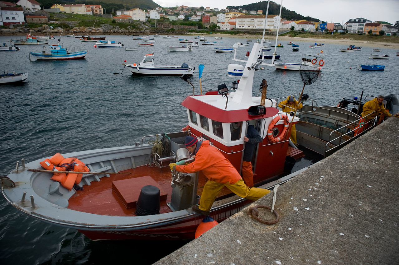 Un pescador salta a su embarcación de arte de enmalle en Lira, A Coruña.