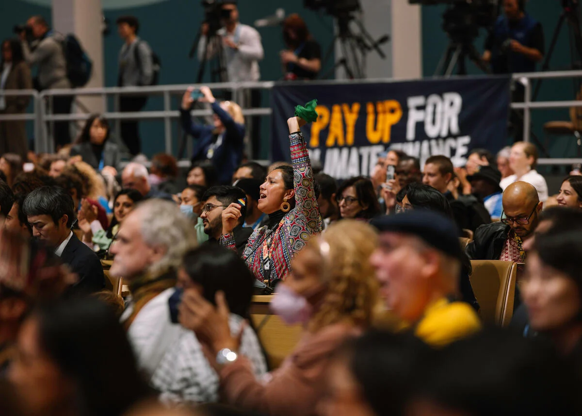 Activista levanta el brazo en señal de solidaridad en la sesión plenaria de los pueblos de la COP29 en Bakú, Azerbaiyán, noviembre de 2024.