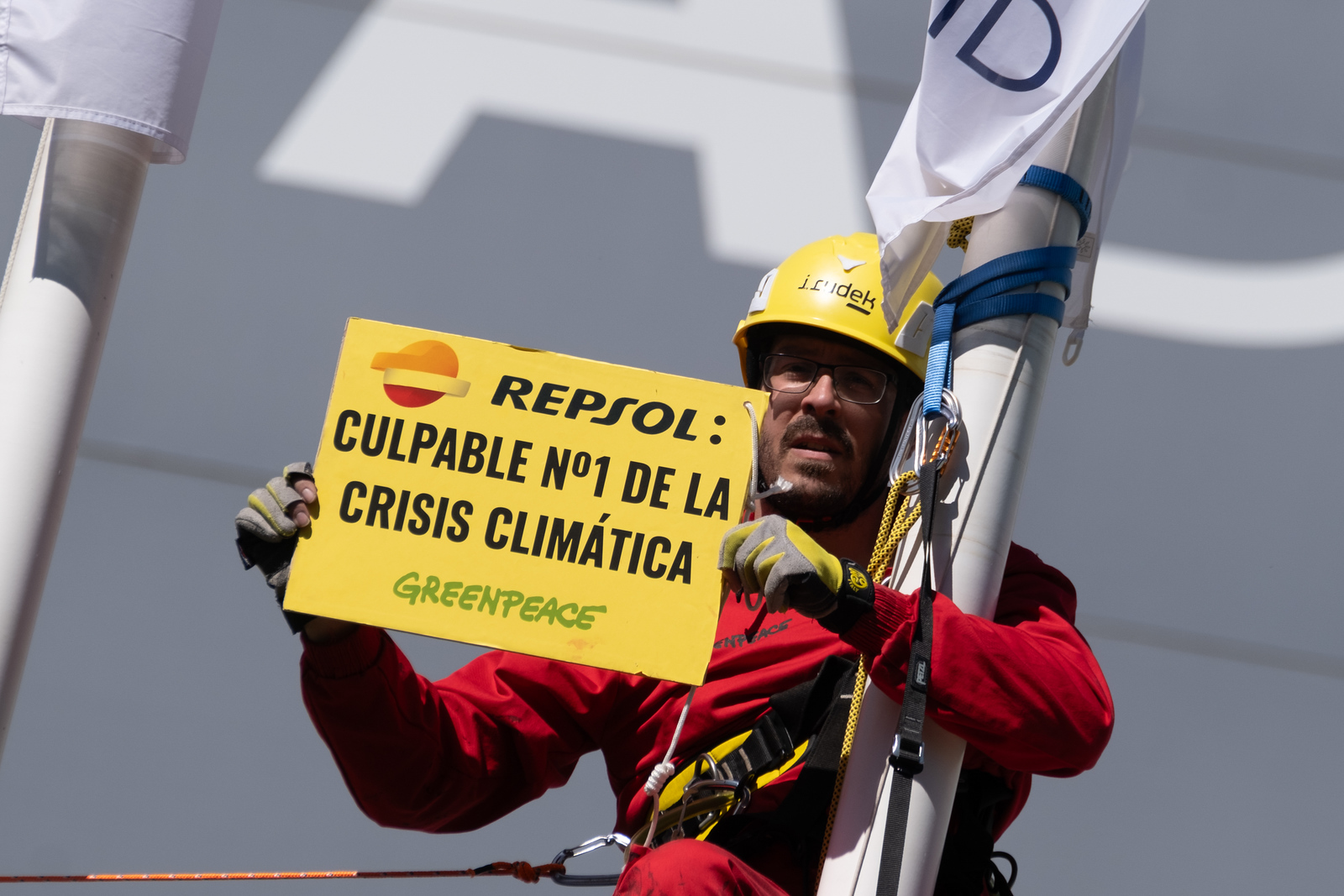 Activista de Greenpeace sostiene un cartel que dice "Repsol: culpable número 1 de la crisis climática"