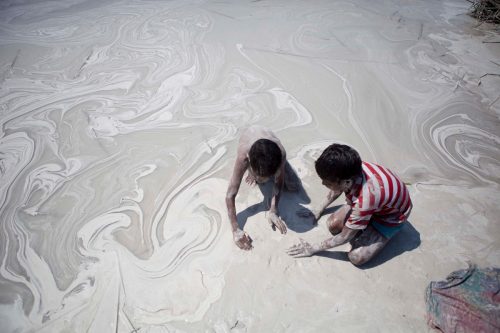 Niños jugando con las cenizas tóxicas en el agua procedentes de la central térmica de Bhusawal, en la India